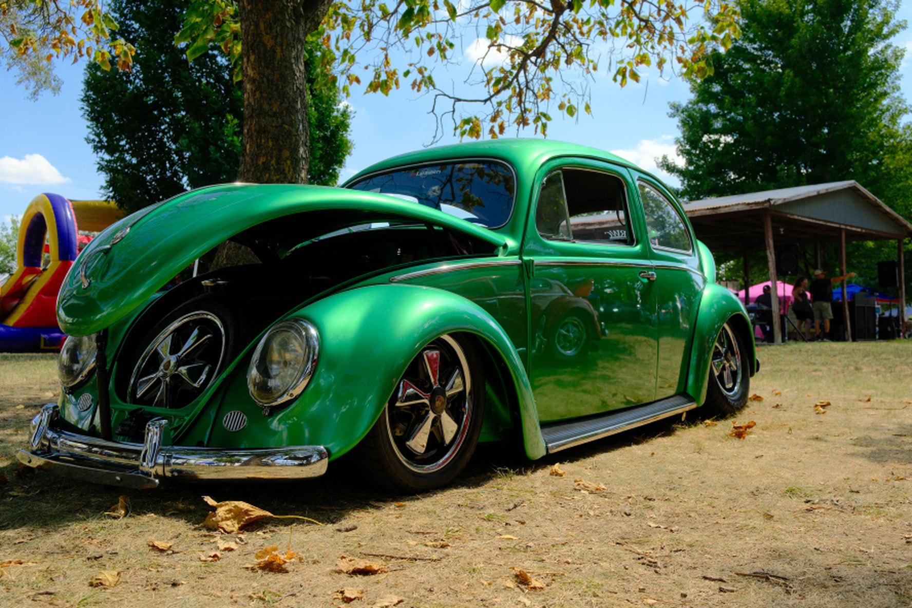 The 2026 Legacy Award winner, a metallic green 1955 Wolfsburg Edition Beetle, in full side profile on the show field